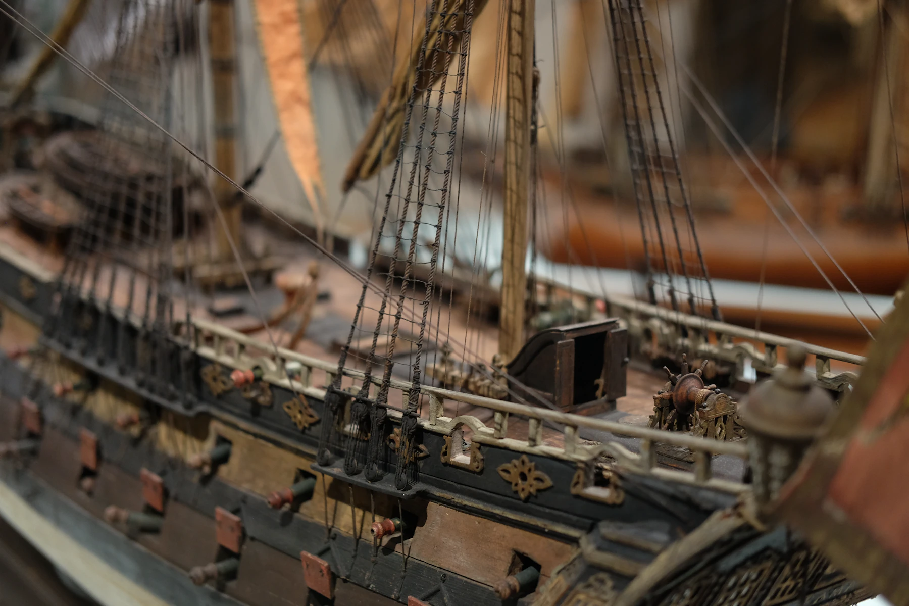 Close-up of a rigged wooden model warship with gun ports, shrouds and deck fittings