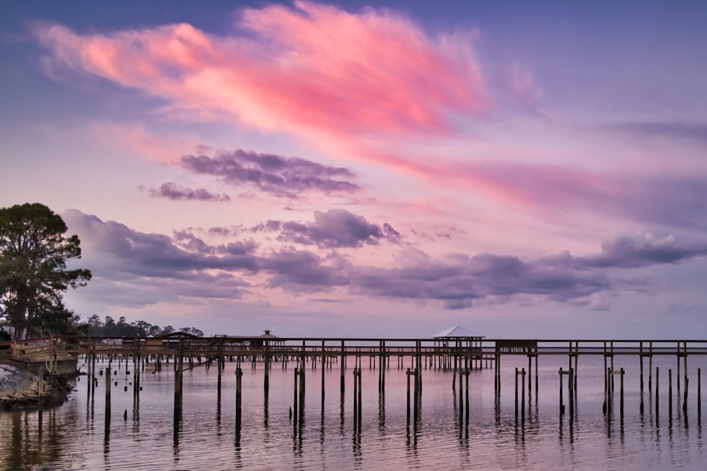 Una nube rosa se cierne sobre un muelle en el agua