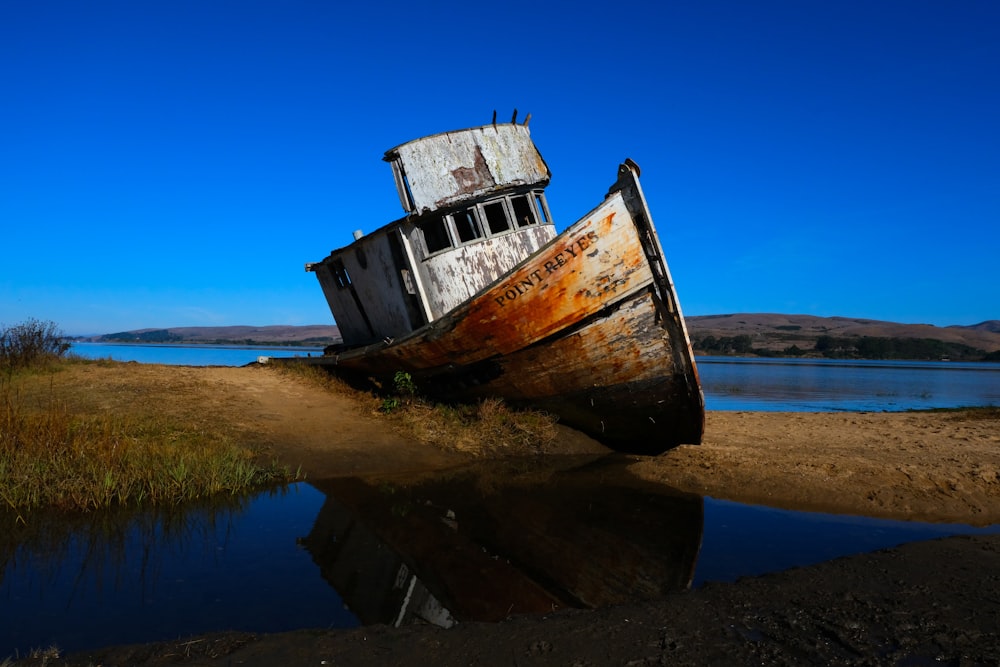 a rusted boat sitting on top of a sandy beach