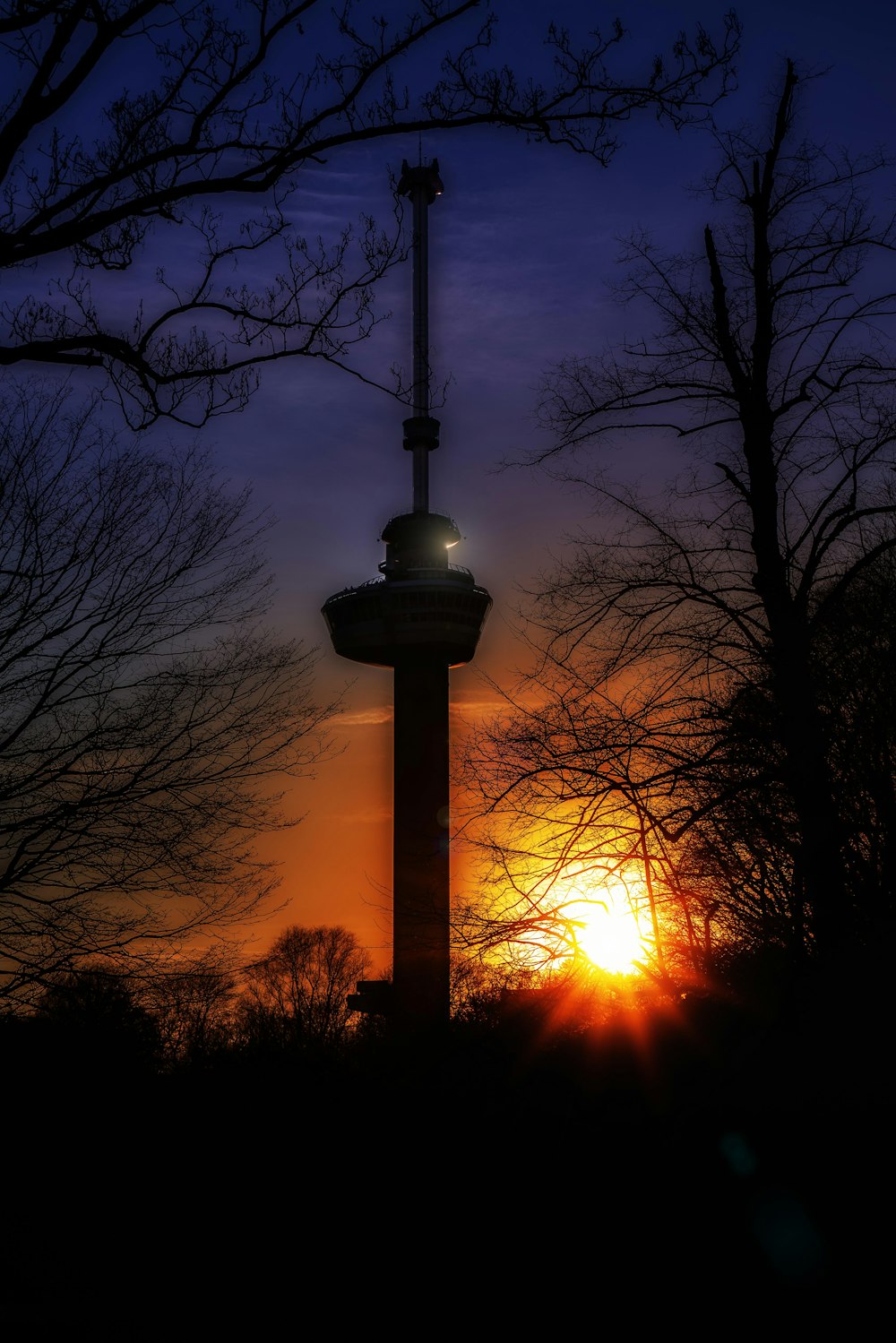 the sun is setting behind a tower with a clock on it