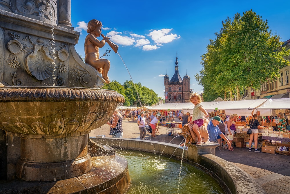 a little girl sitting on top of a fountain