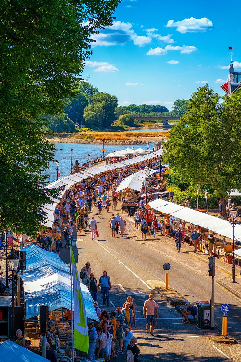 a crowd of people walking down a street next to a river