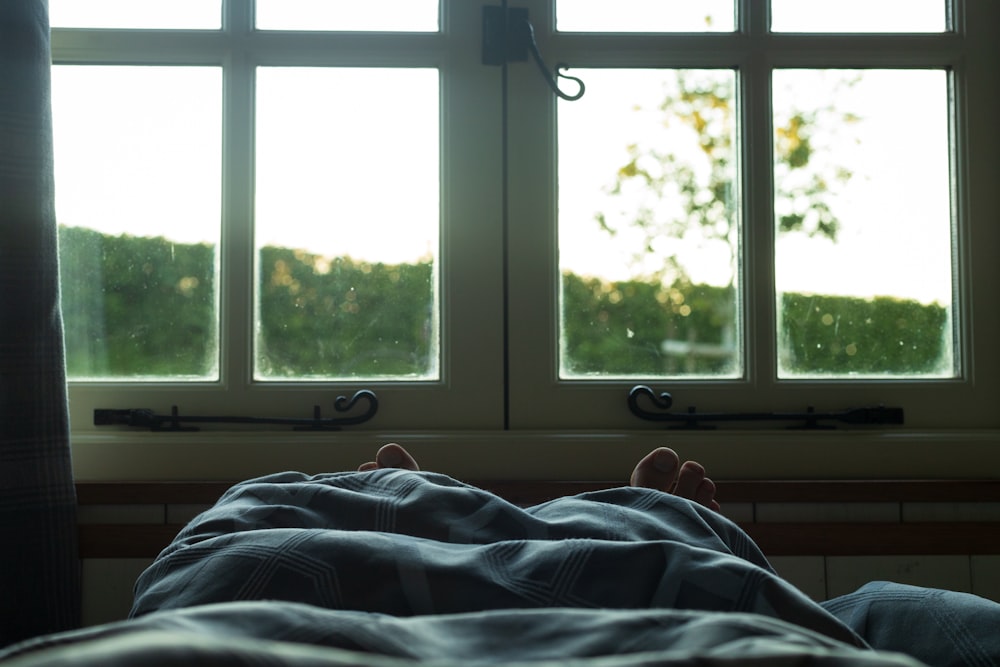 a person laying on a bed in front of a window