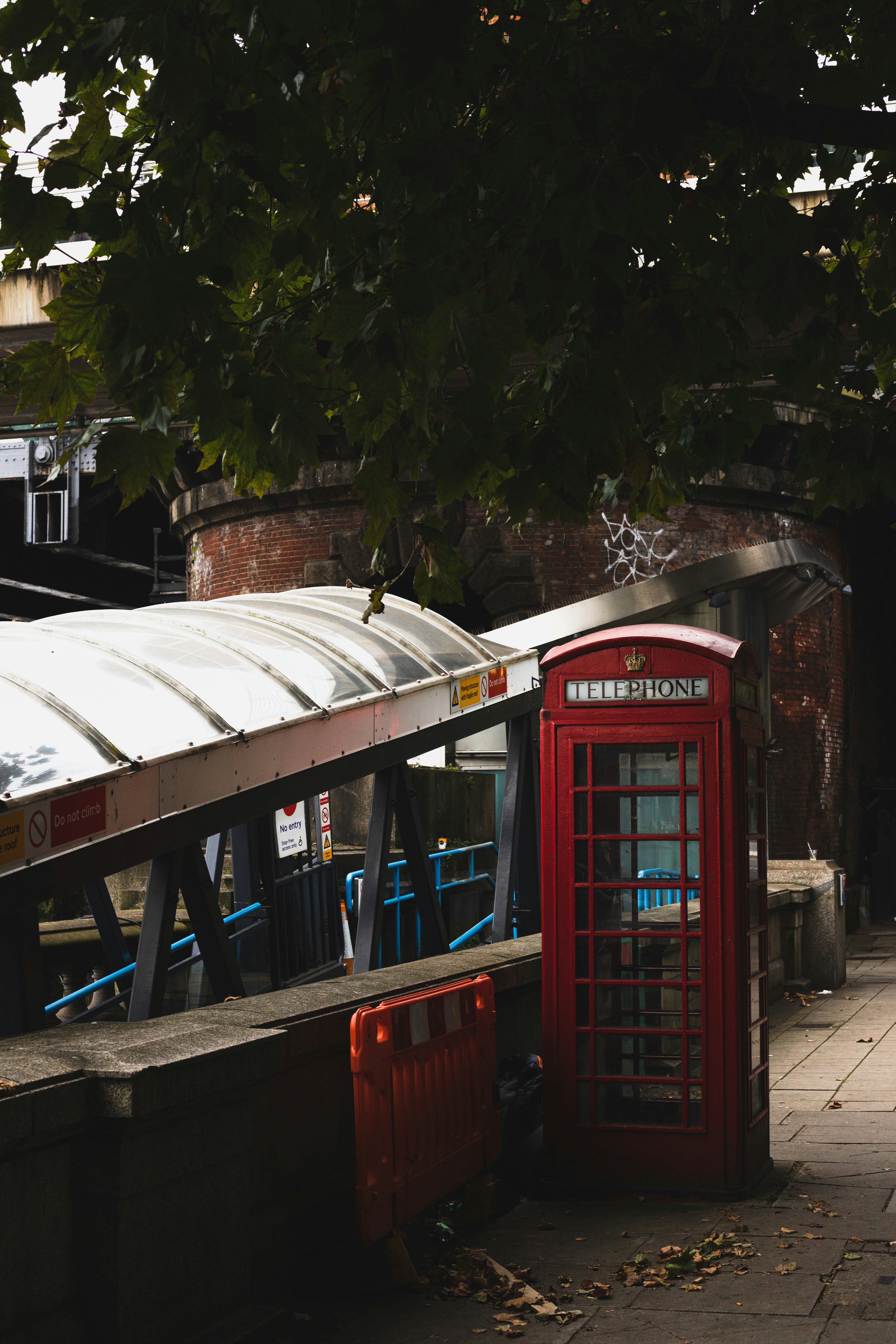 a red phone booth sitting next to a tree