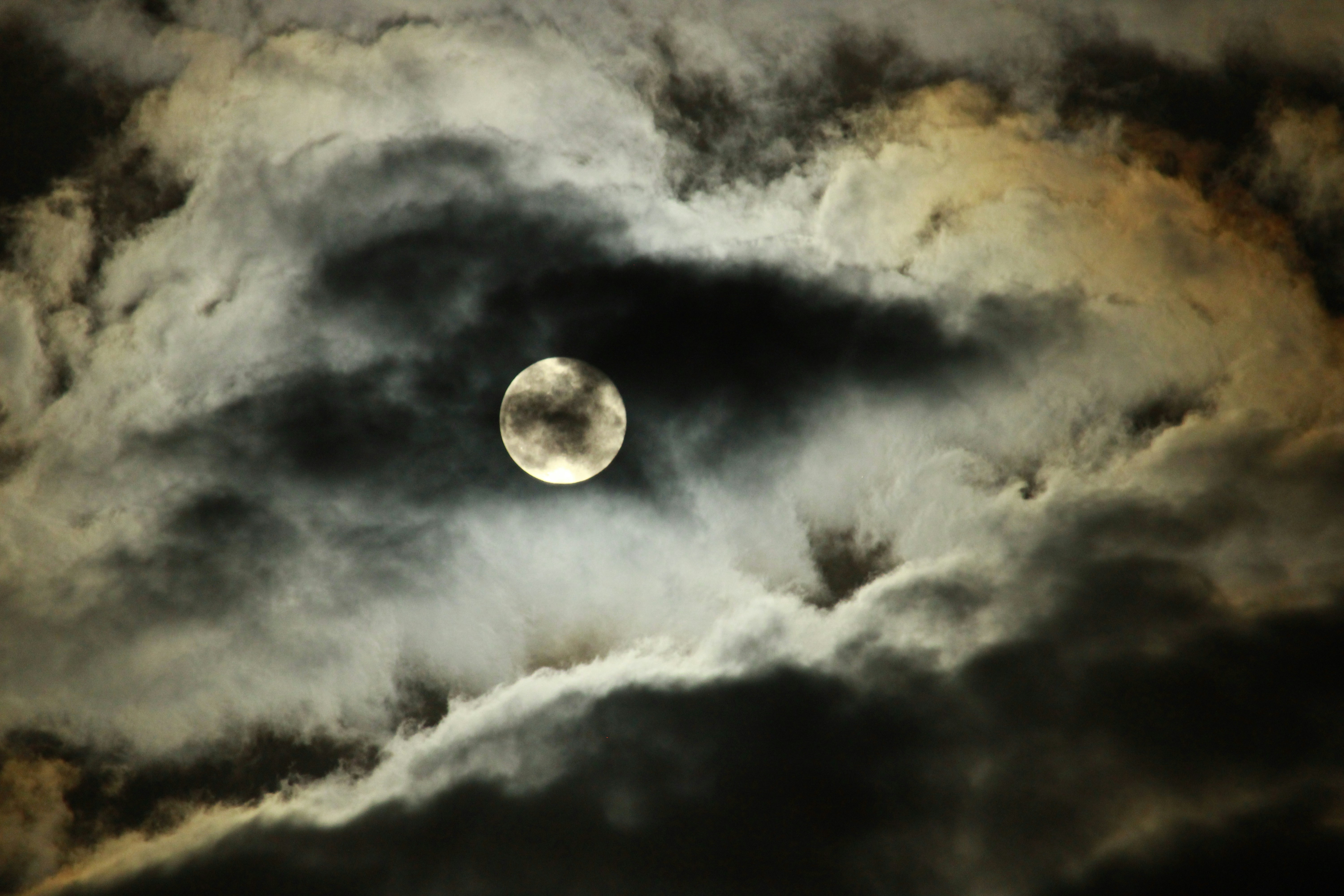 a full moon is seen through the clouds
