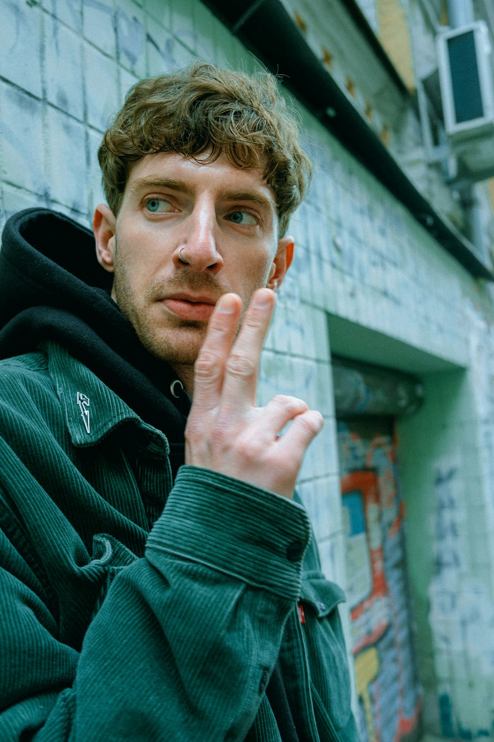 a man standing in front of a building making a hand gesture