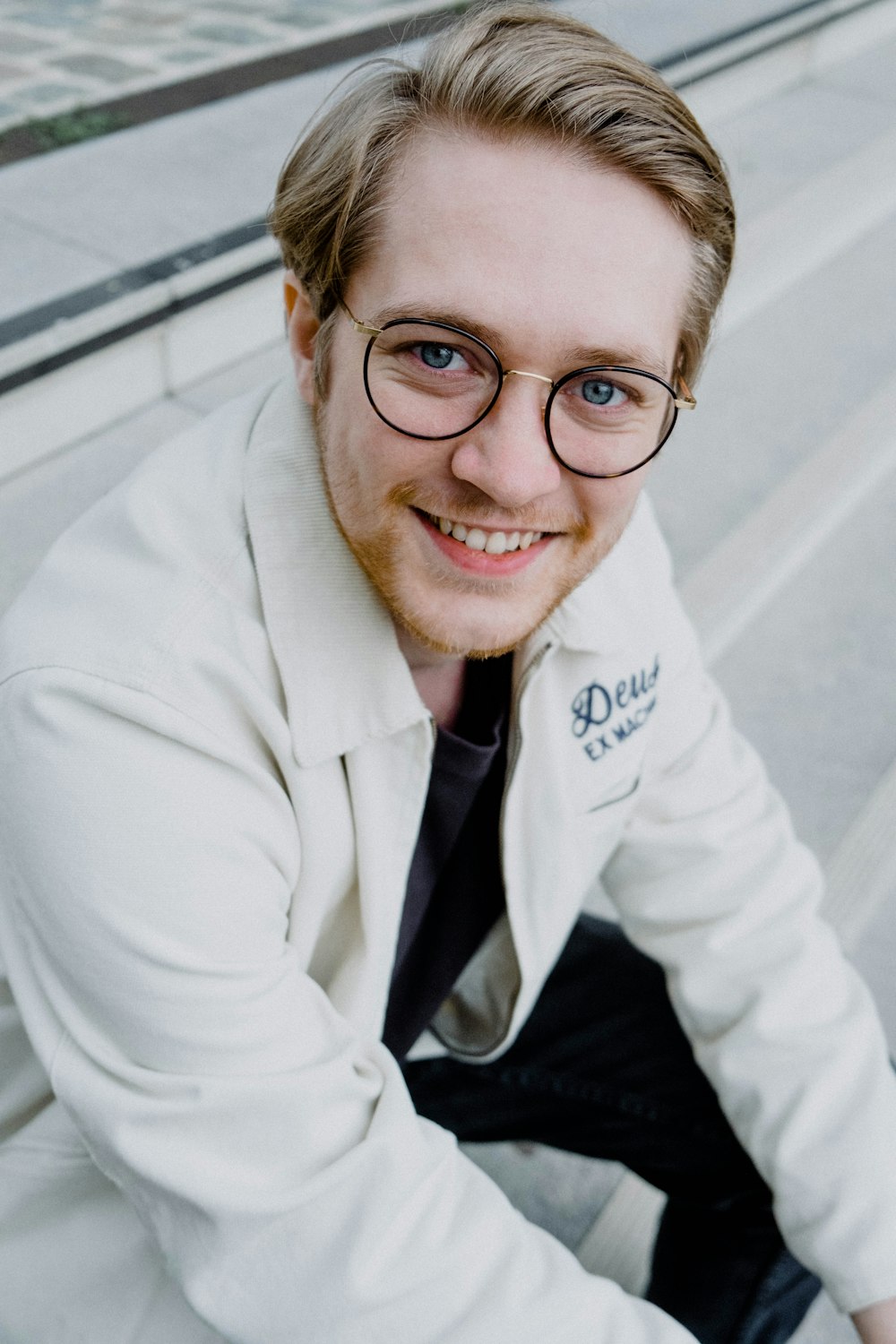 a man wearing glasses and a white jacket