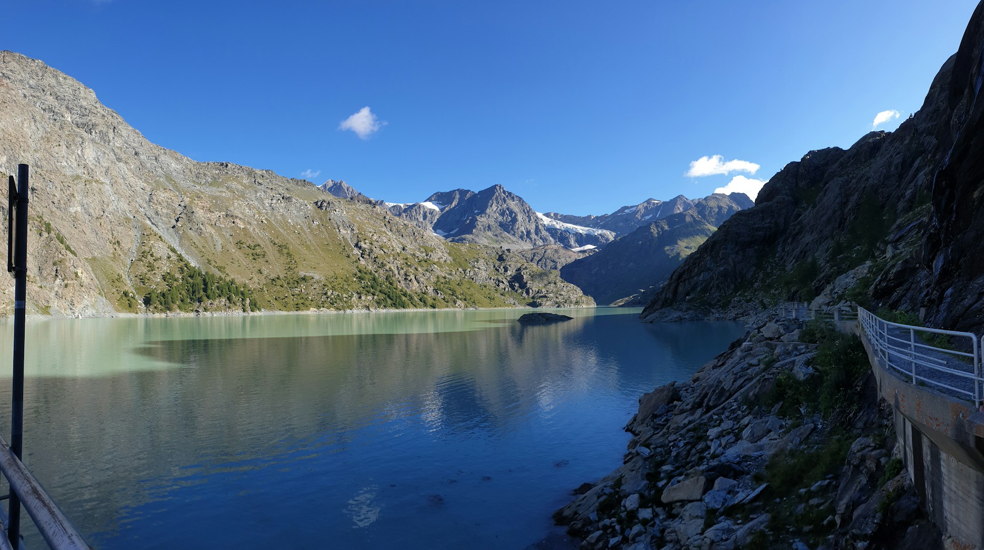 A serene vertical image of a mountain lake reflecting the clear blue sky.