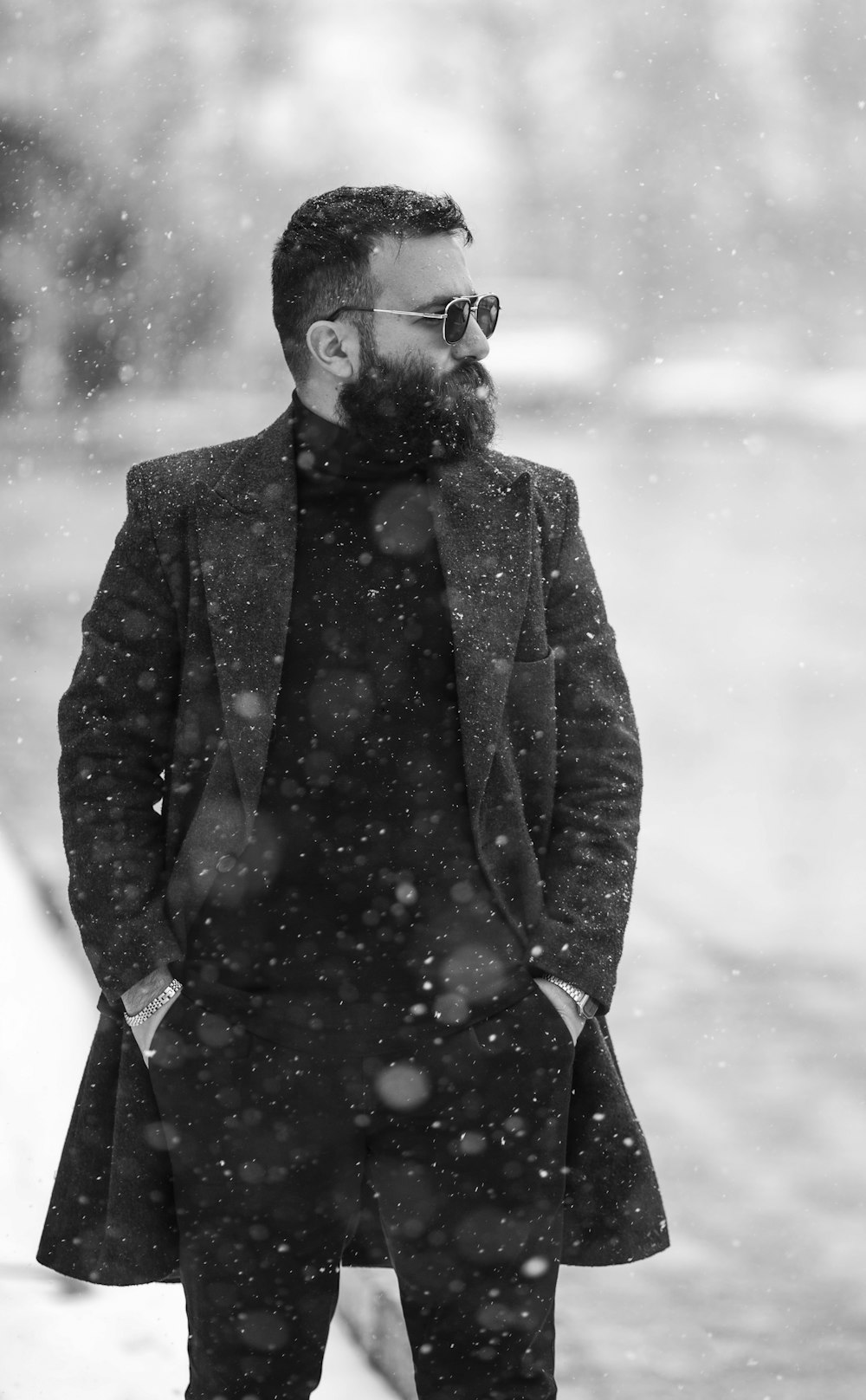 a man in a coat and sunglasses standing in the snow