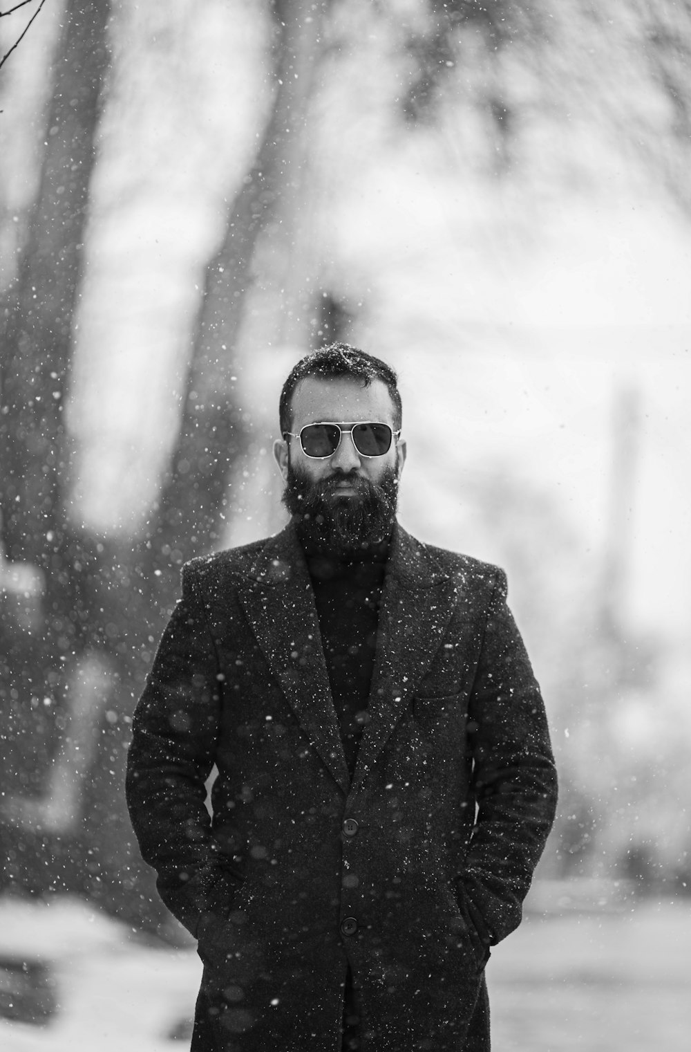 a man with a beard and sunglasses standing in the snow