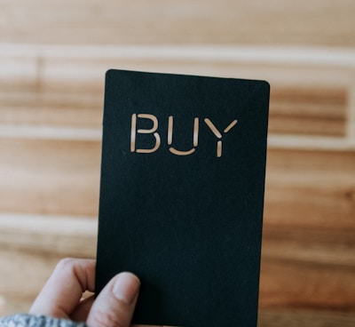 a person holding up a black book with the word buy written on it