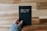 a person holding a black book with the word buy written on it