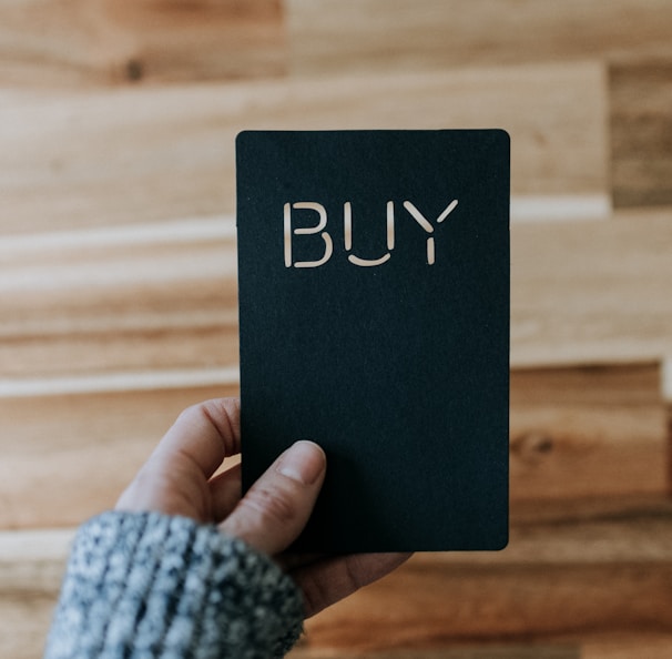 a person holding a black book with the word buy written on it