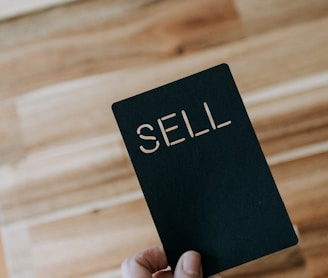 a person holding a black book with the word sell written on it