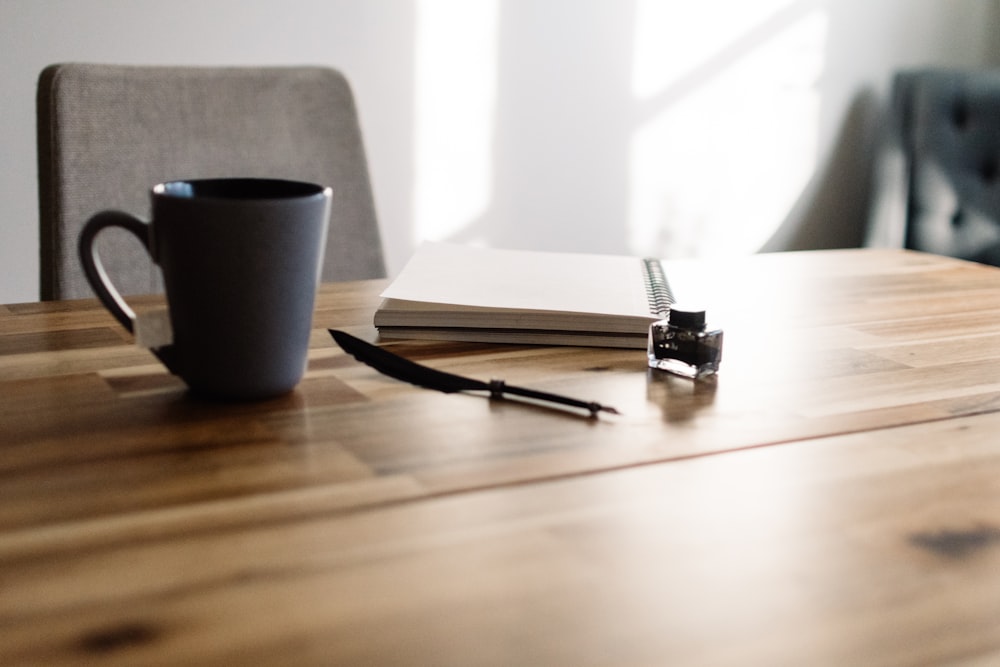 un tavolo con un quaderno, una penna e una tazza di caffè