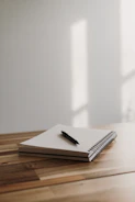 A peaceful scene of a journal and pen resting on a wooden table with natural light.