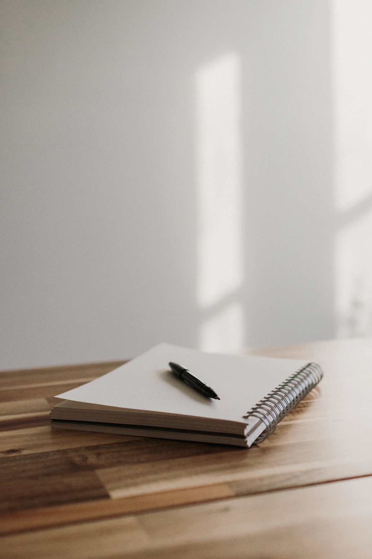 An open notebook with a pen resting on a wooden table