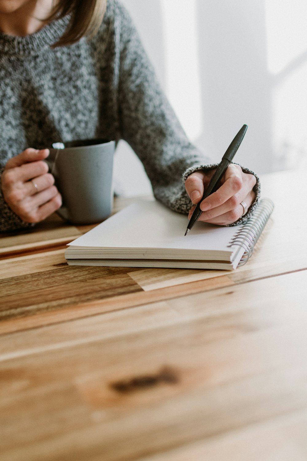 a woman sitting at a table writing on a notebook