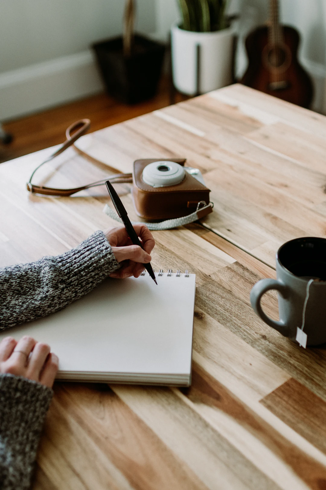 Overhead view of a writer’s hands working in a notebook on a wooden table