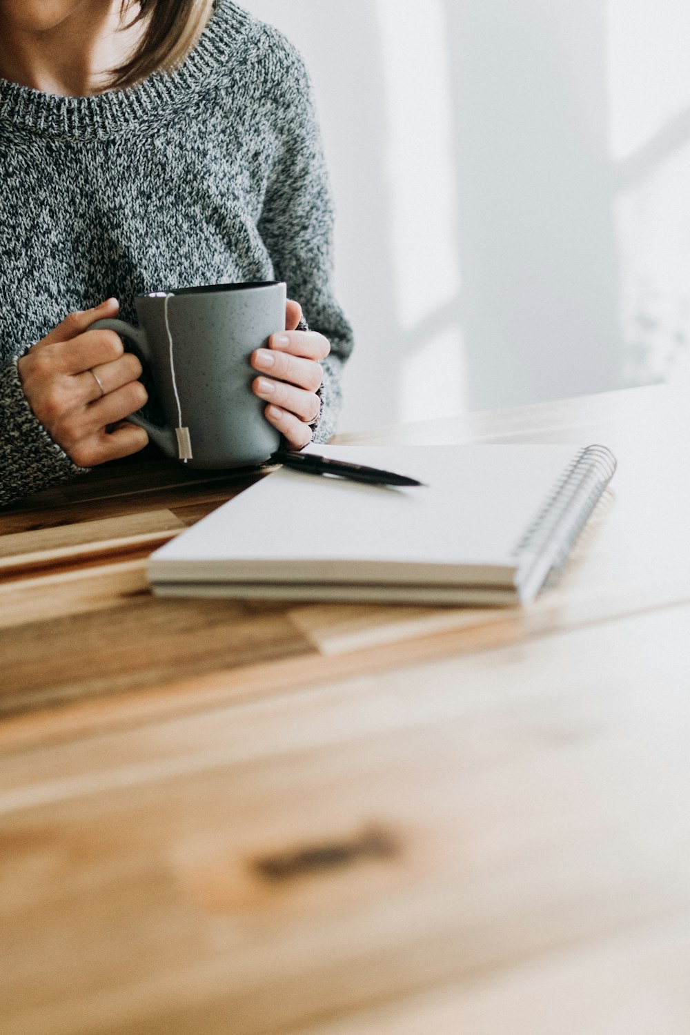 a woman sitting at a table holding a cup of coffee