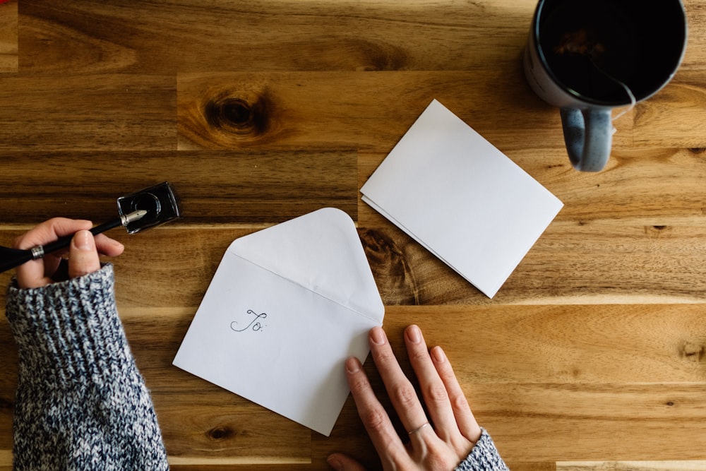 a person writing on a piece of paper next to a cup of coffee