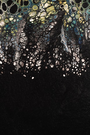 Abstract art depicting a multitude of cell-like shapes in varying sizes, resembling a biological or chemical pattern, with colors transitioning from yellow and green at the top to blue and black at the bottom.