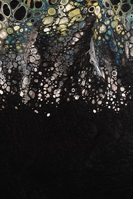 Abstract art depicting a multitude of cell-like shapes in varying sizes, resembling a biological or chemical pattern, with colors transitioning from yellow and green at the top to blue and black at the bottom.