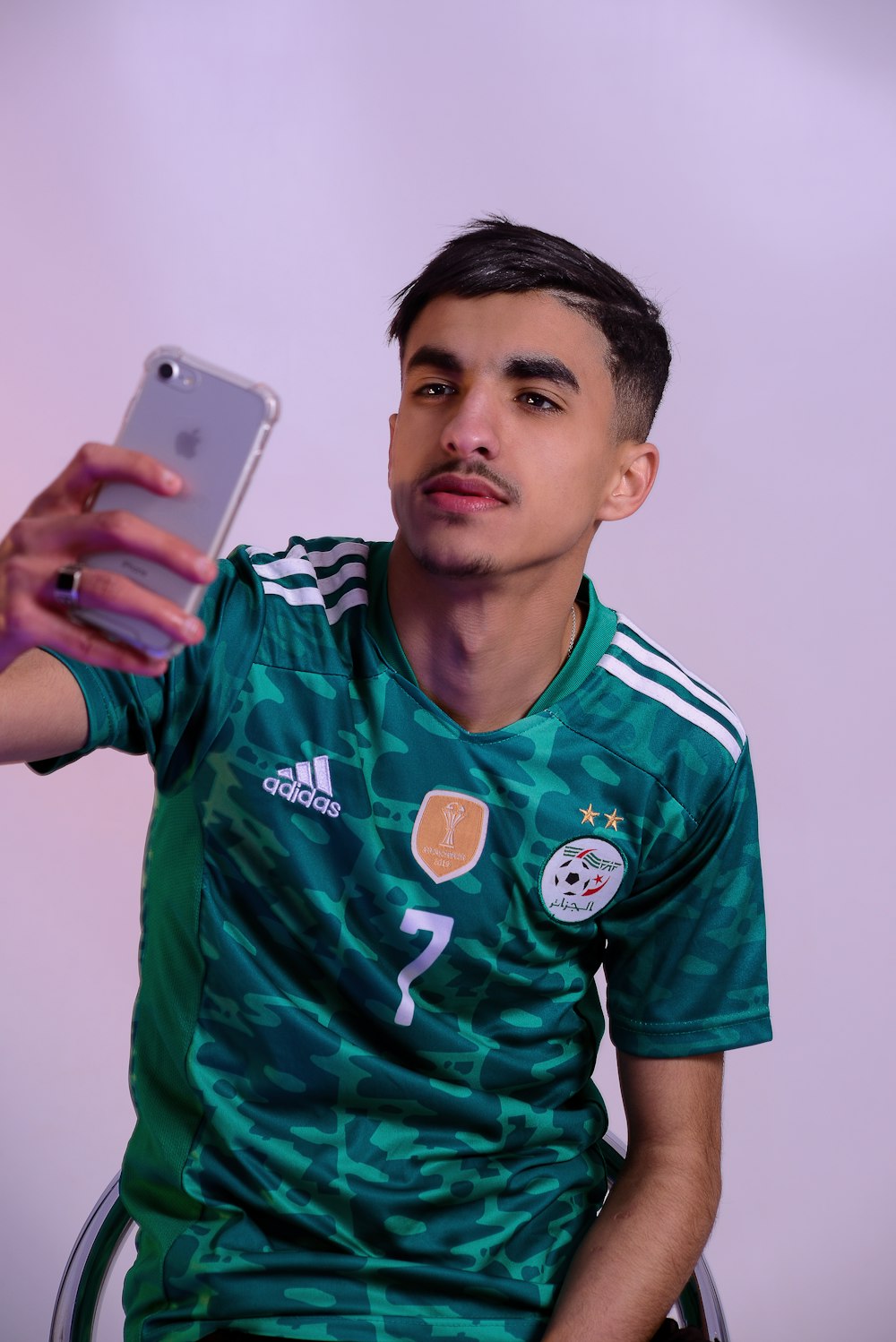 a man in a green shirt holding a cell phone