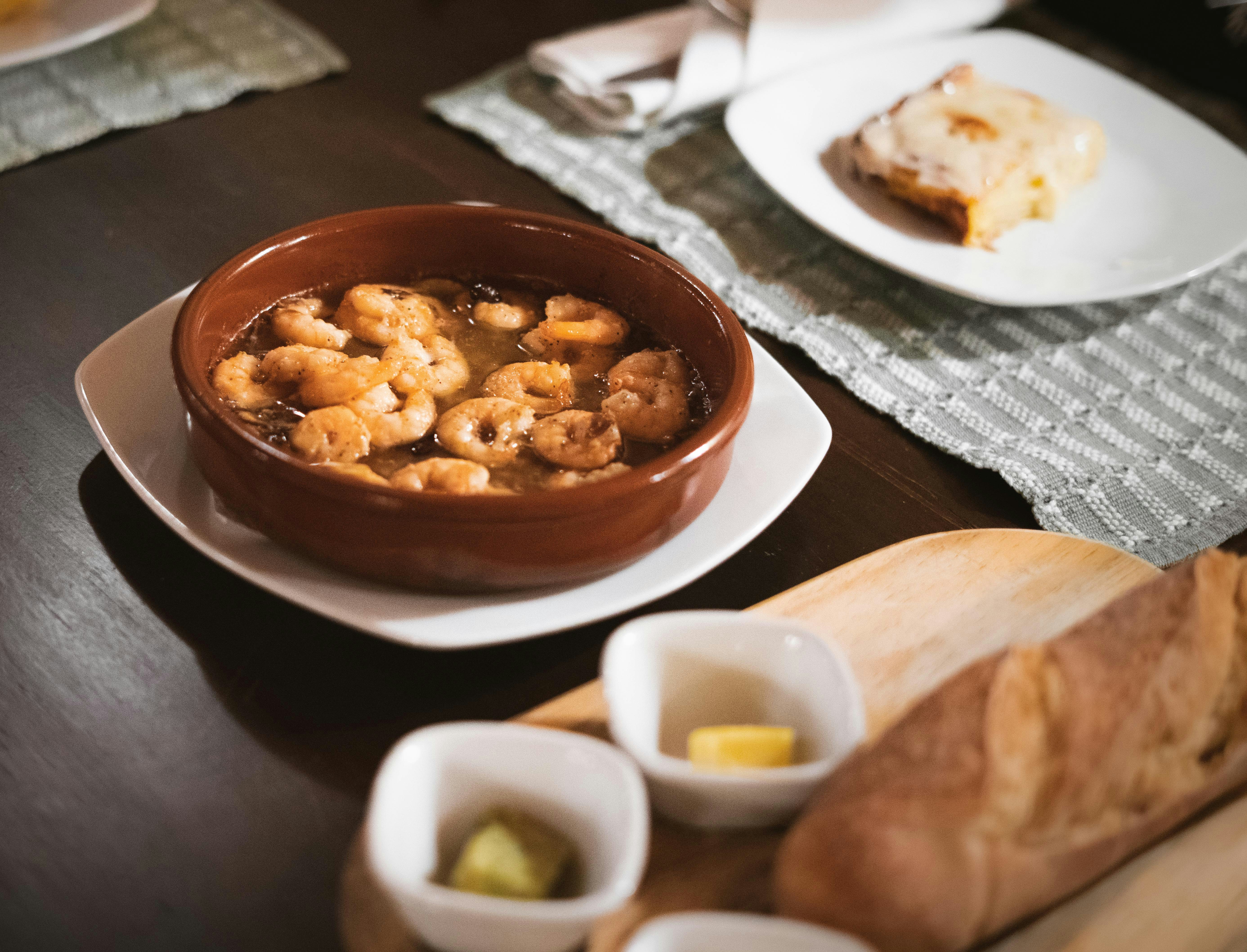 Chili garlic shrimp in a dark ceramic bowl with vibrant red sauce and fresh herbs