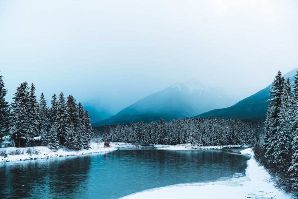 a lake surrounded by snow covered trees and mountains
