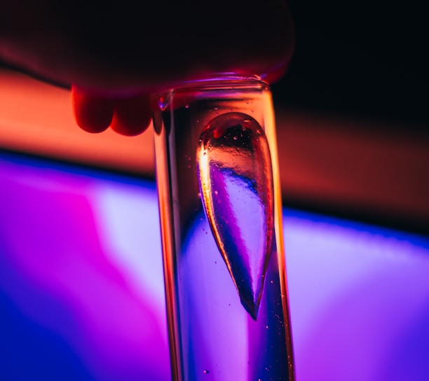 a close up of a person holding a glass in front of a computer screen