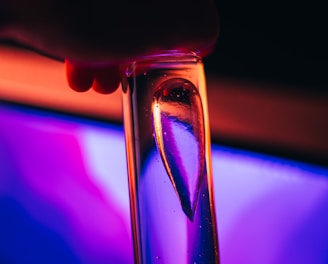 a close up of a person holding a glass in front of a computer screen