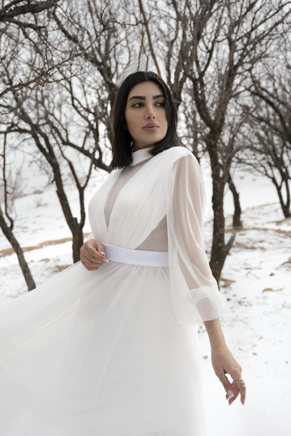 a woman in a white dress standing in the snow