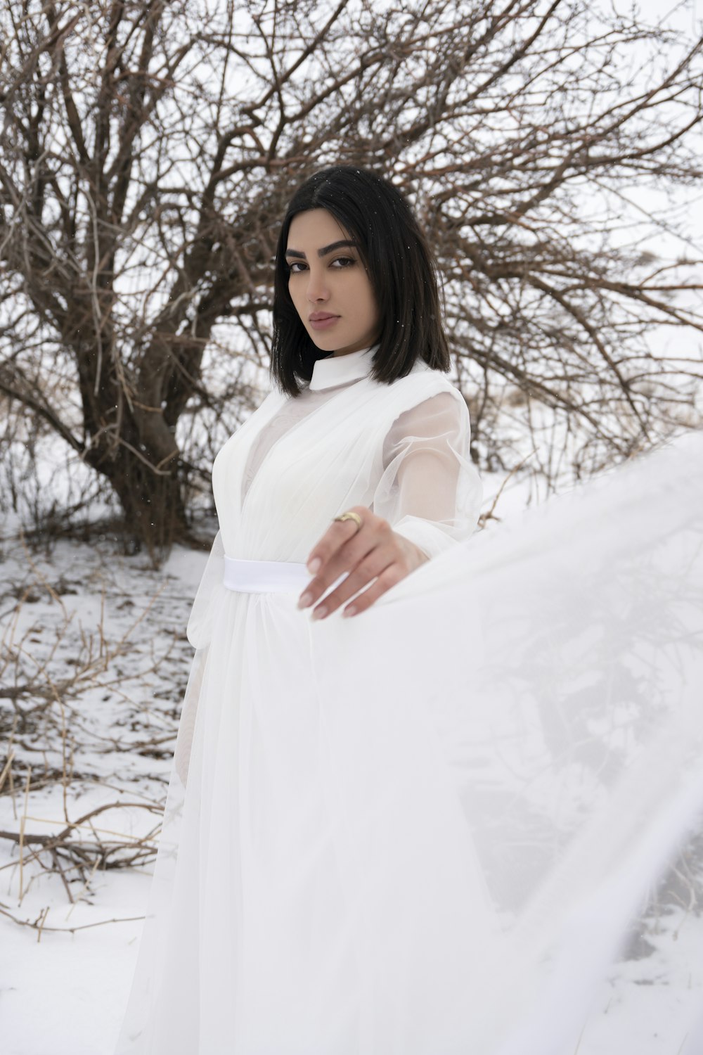 a woman in a white dress standing in the snow