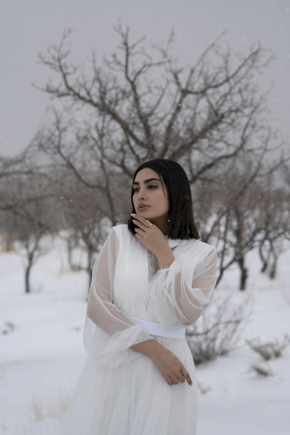 a woman in a white dress standing in the snow