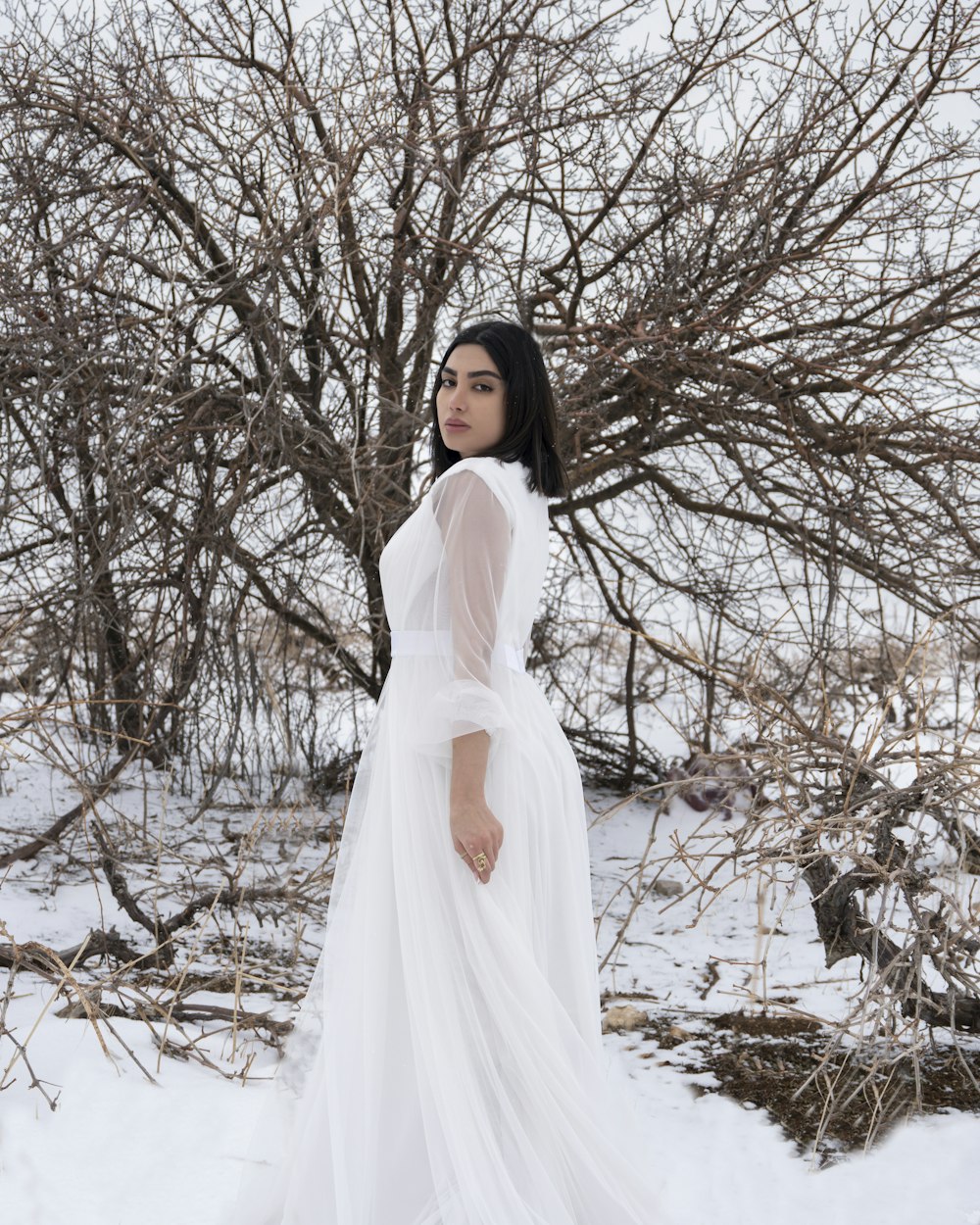 a woman in a white dress standing in the snow