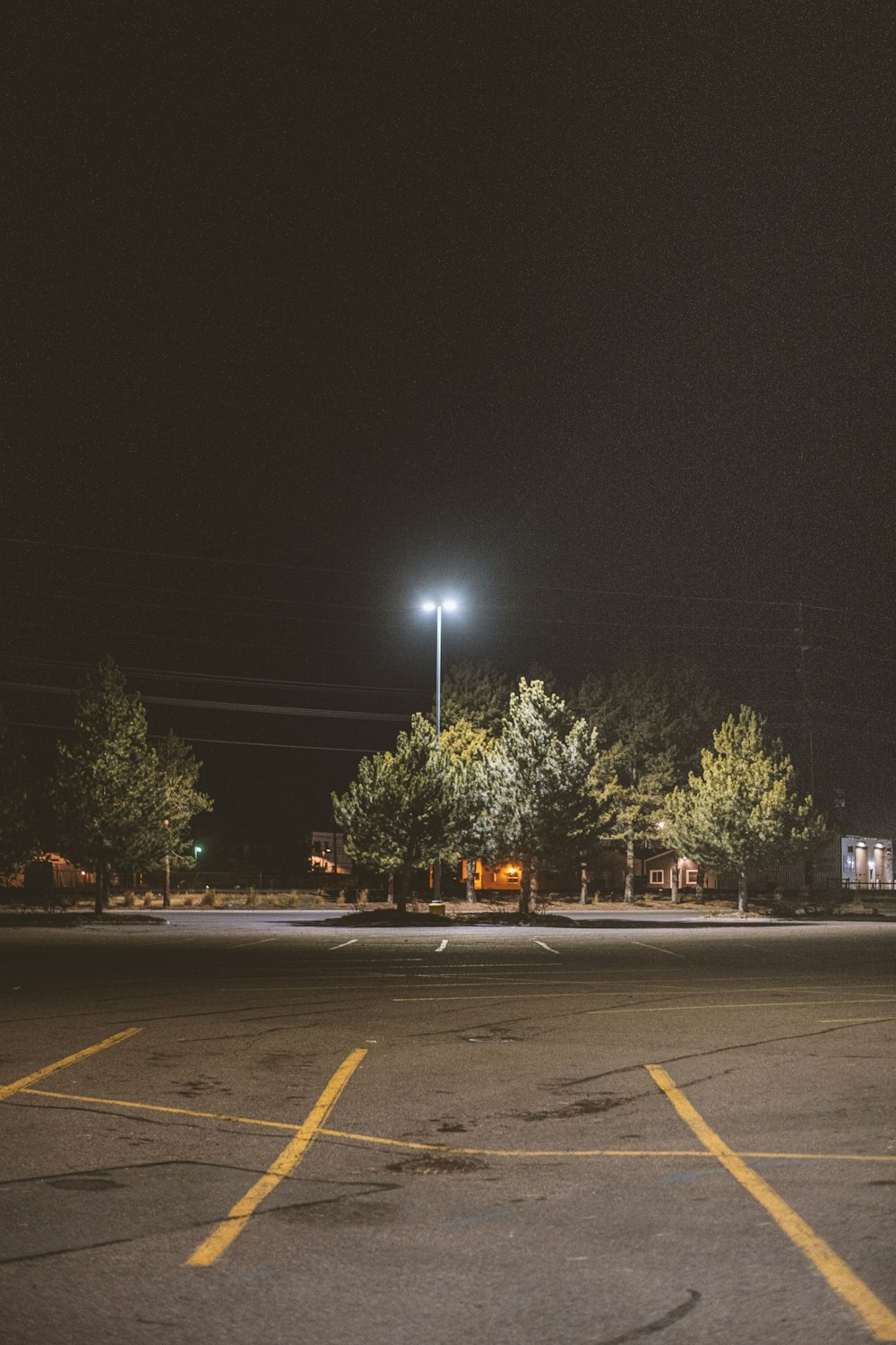 an empty parking lot at night with a street light in the background