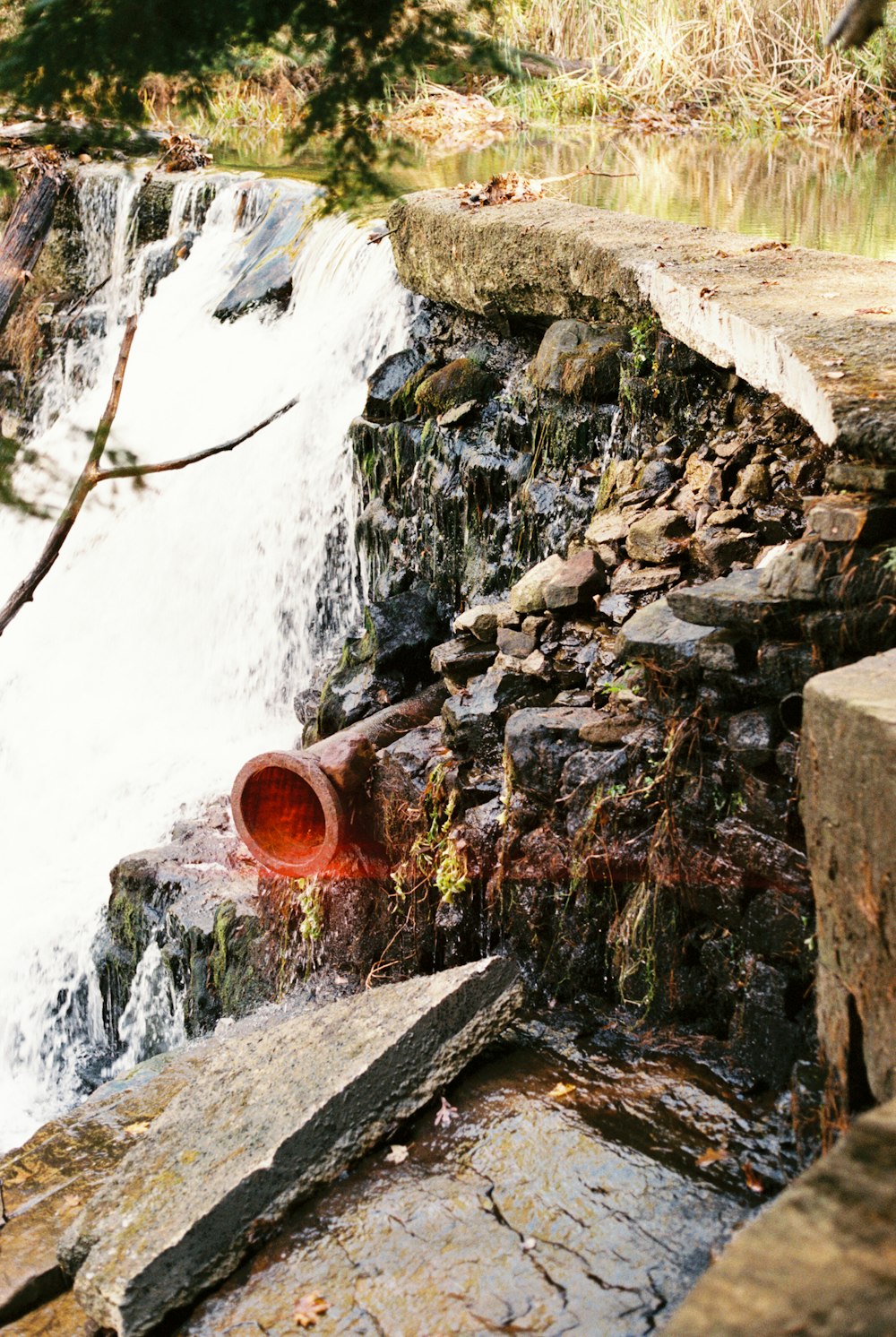 a large pipe that is next to a waterfall