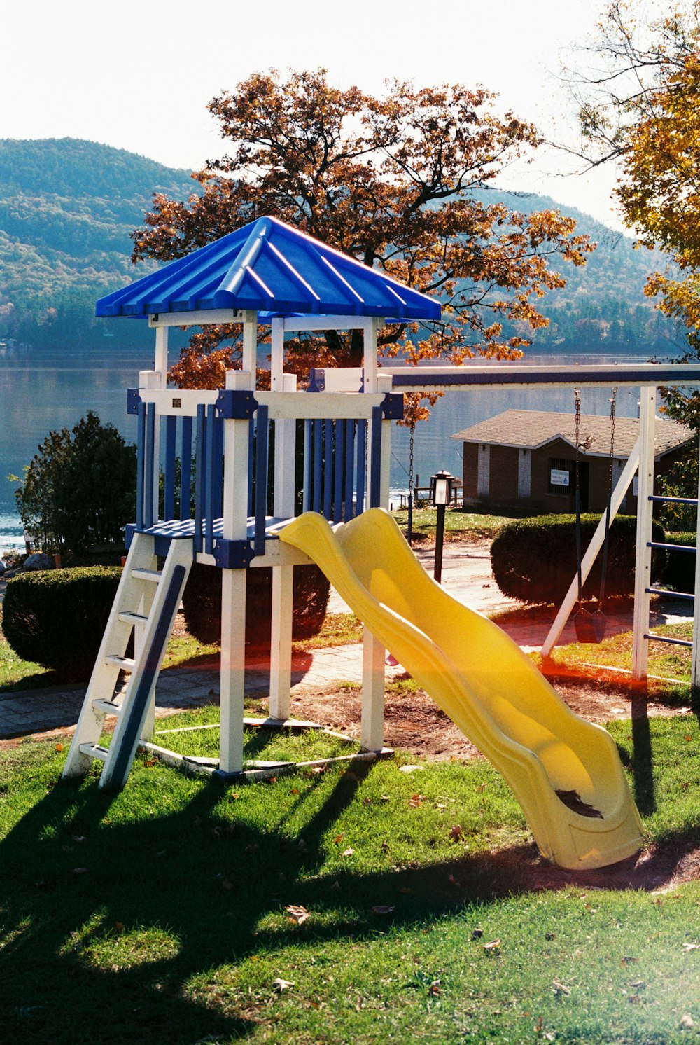 a playground with a yellow slide and a blue umbrella