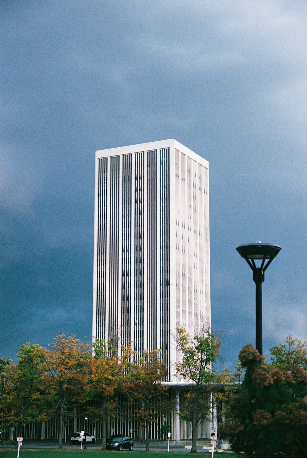 a tall white building sitting next to a lush green park