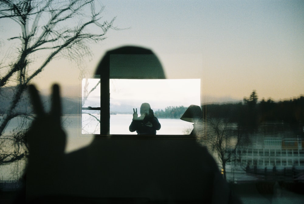 a person taking a picture of a lake through a window
