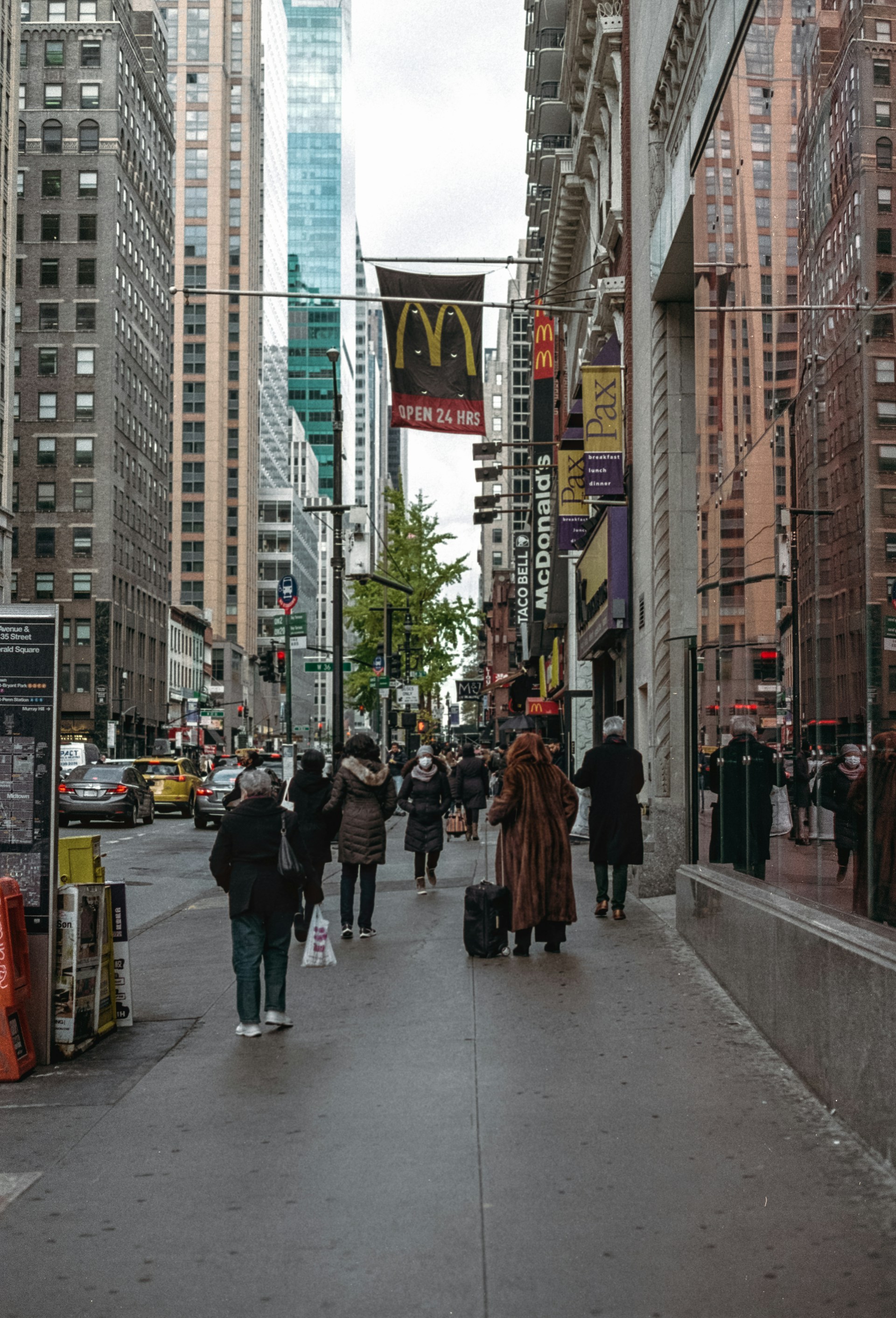 a group of people walking down a street next to tall buildings