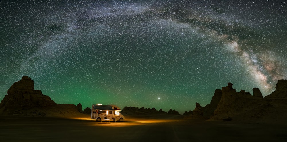 a truck parked in the middle of a desert under a night sky filled with stars