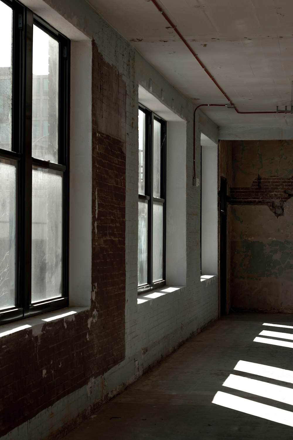 an empty room with three windows and a brick wall