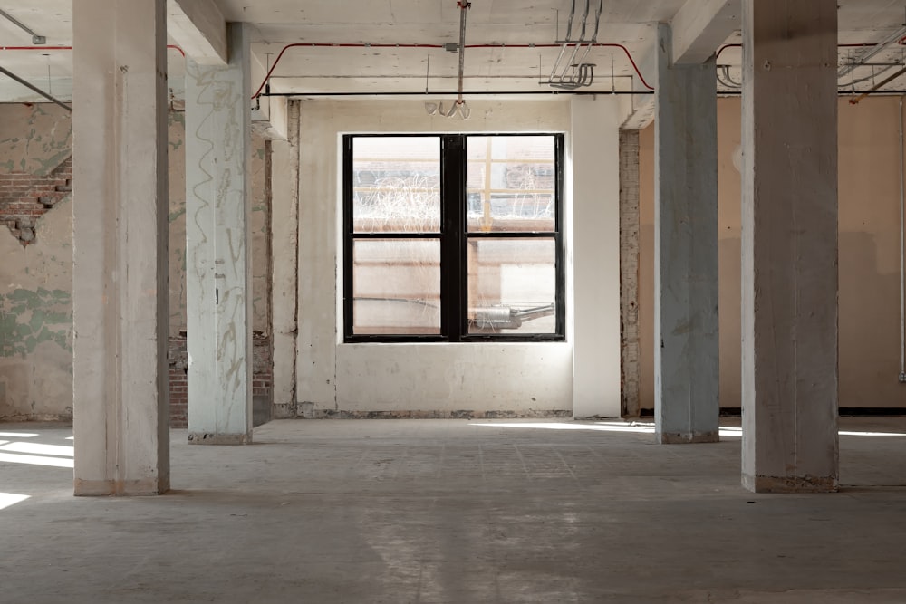 an empty room with exposed pipes and windows