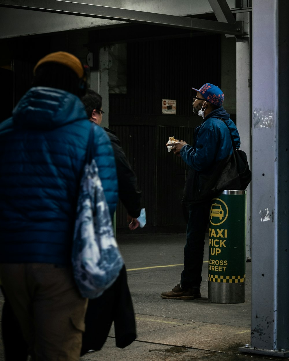 um homem em uma jaqueta azul está comendo um pedaço de comida