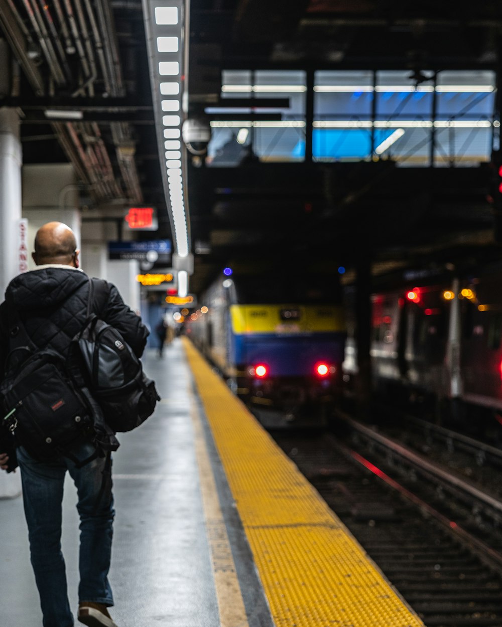 a man with a backpack is waiting for a train