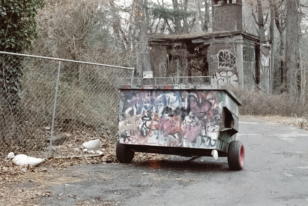 a dump truck with graffiti on it parked in front of a fence