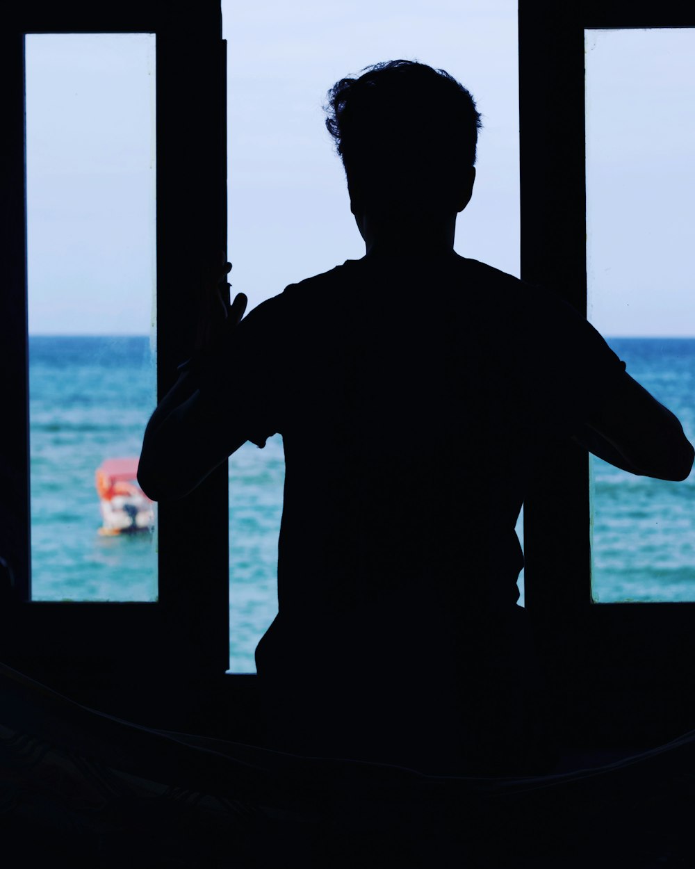 a man standing in front of a window next to the ocean