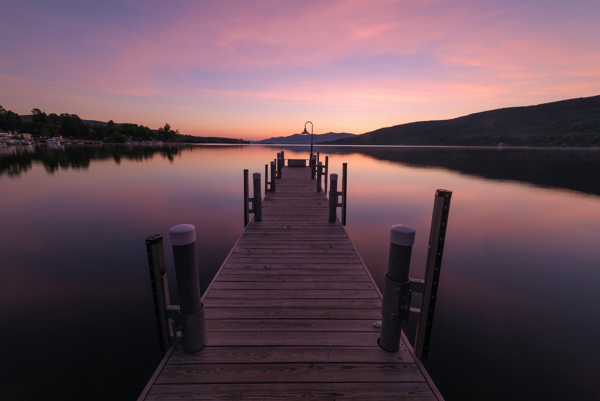 A wooden dock reaching into Lake George at dawn